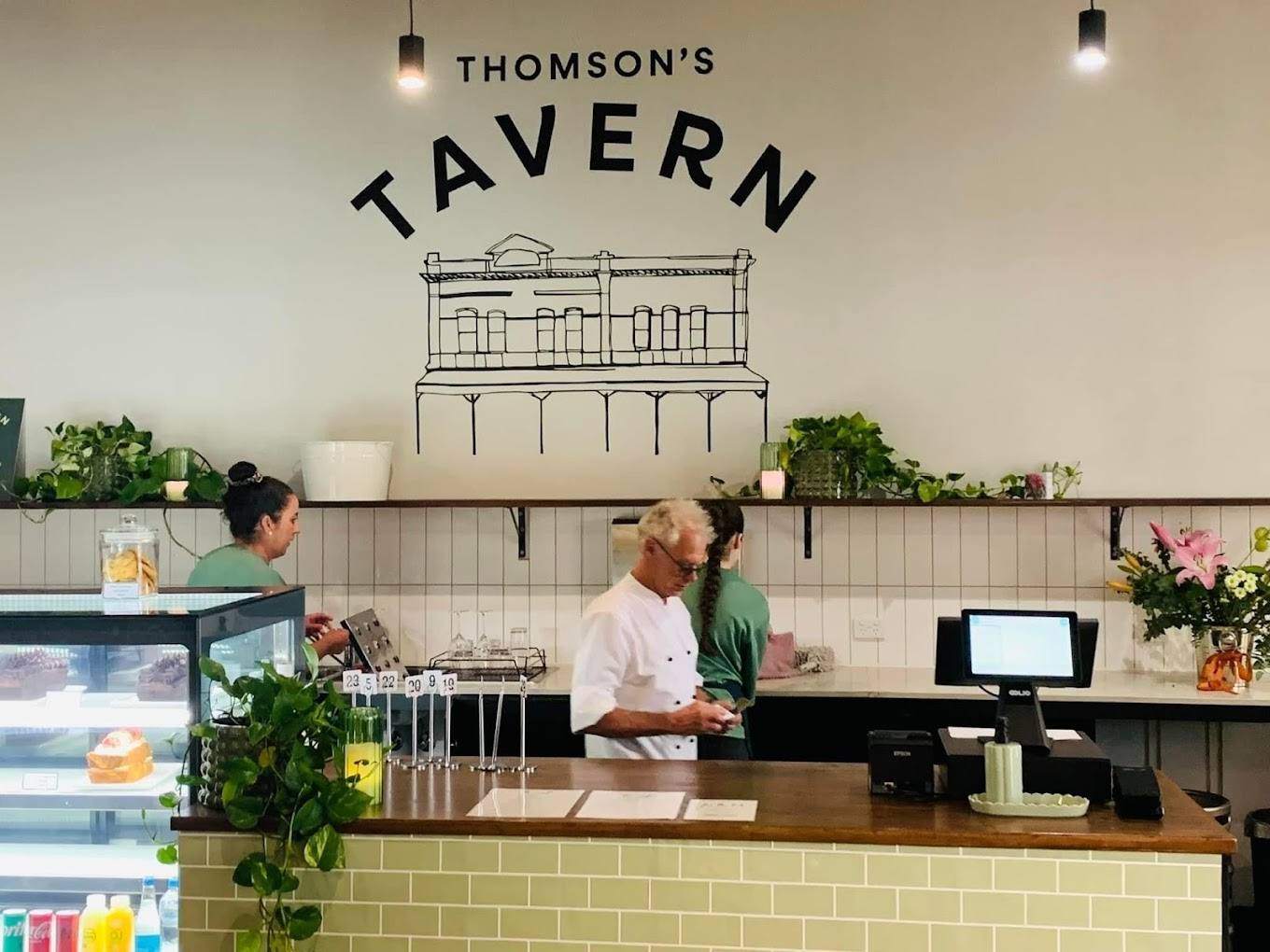 The counter at Thomson's Tavern, with the painted logo on the wall above the cake cabinet.