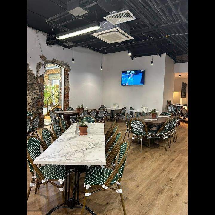 The dining room, with marble tables and green bistro chairs.